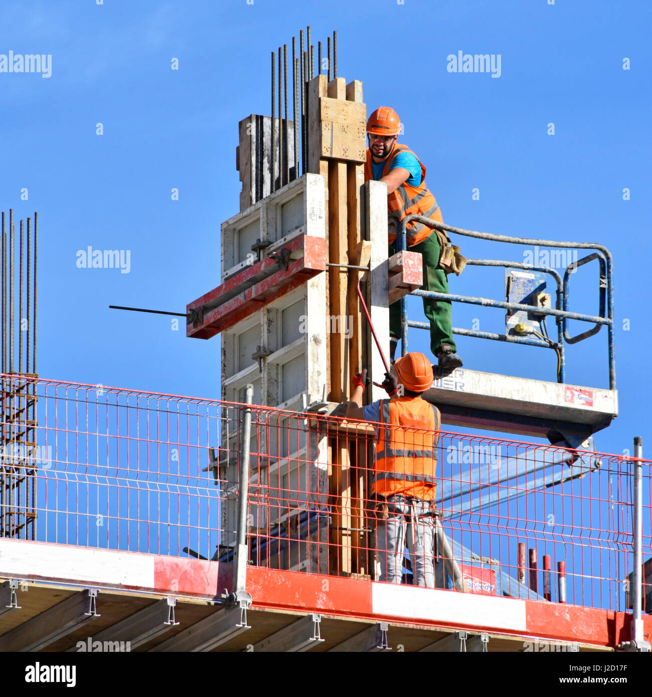 Gesundheit & Sicherheit uk Website Bauarbeiter Befestigung Spalte Schalung Arbeitnehmer tragen Schutzhelme & Warnschutz Jacke am Hochhaus bauen Stockfoto