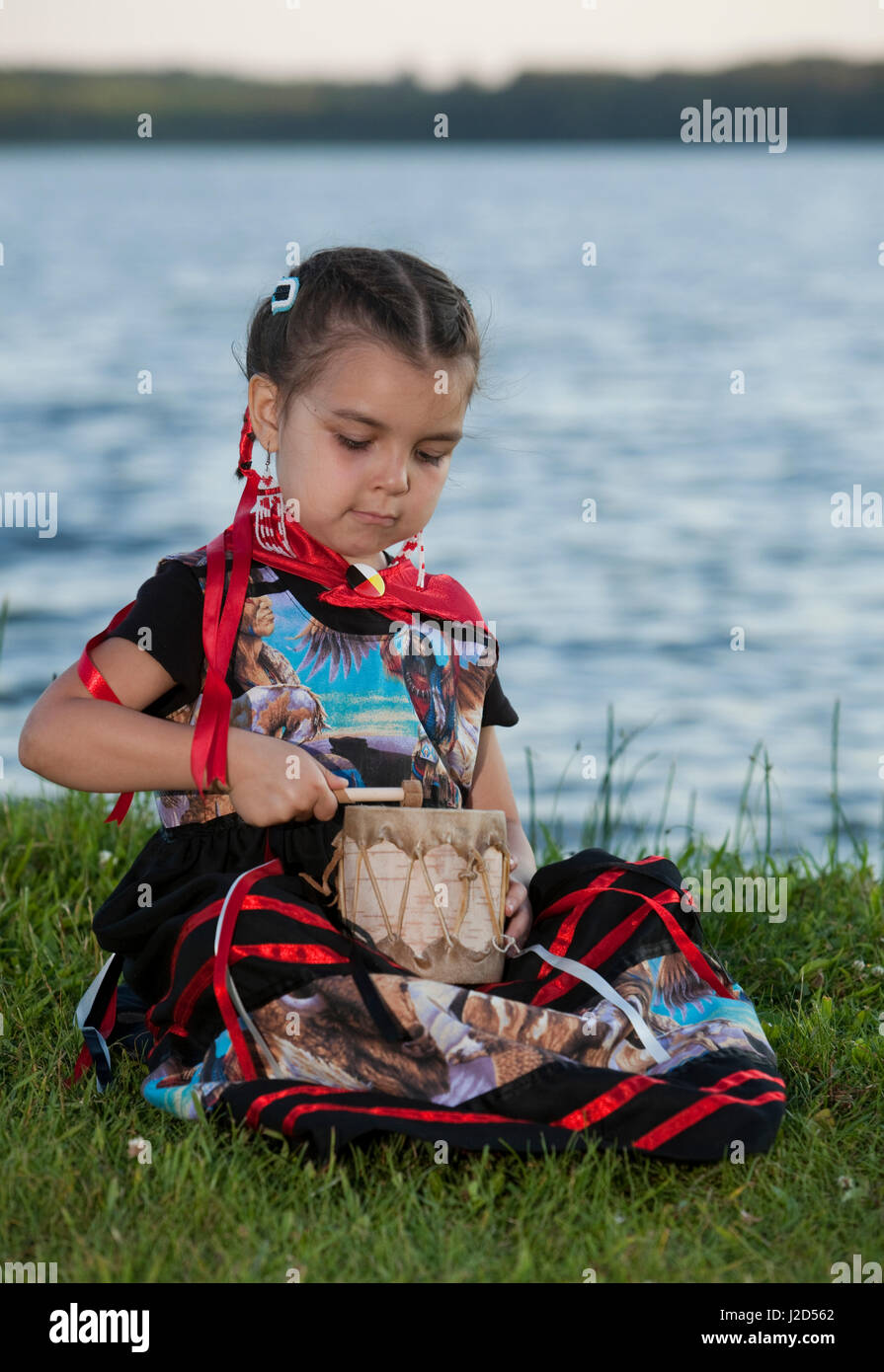 Ojibwe Kind nutzt eine traditionell hergestellte Birkenrinde Tom Tom Drum mit Rohhaut an einem See, Midland Ontario bedeckt. (MR) Stockfoto