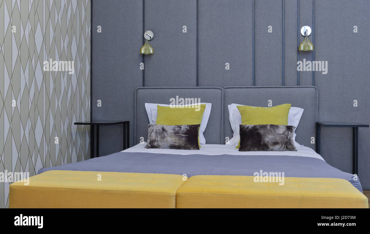 Moderner Luxus Schlafzimmer mit Kingsize Größe, grauen Stoff Kopfteil, gelben Kissen. Stockfoto