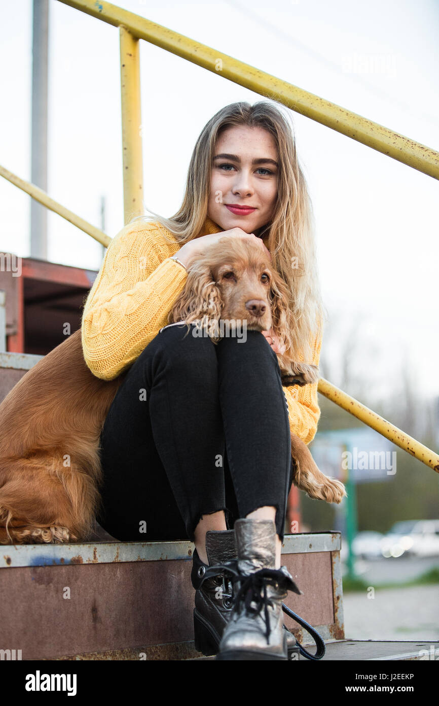 Schöne Blondine sah aus wie Jennifer Aniston sitzen mit einem Cocker Spaniel Hund auf eine Metall-Treppe Stockfoto