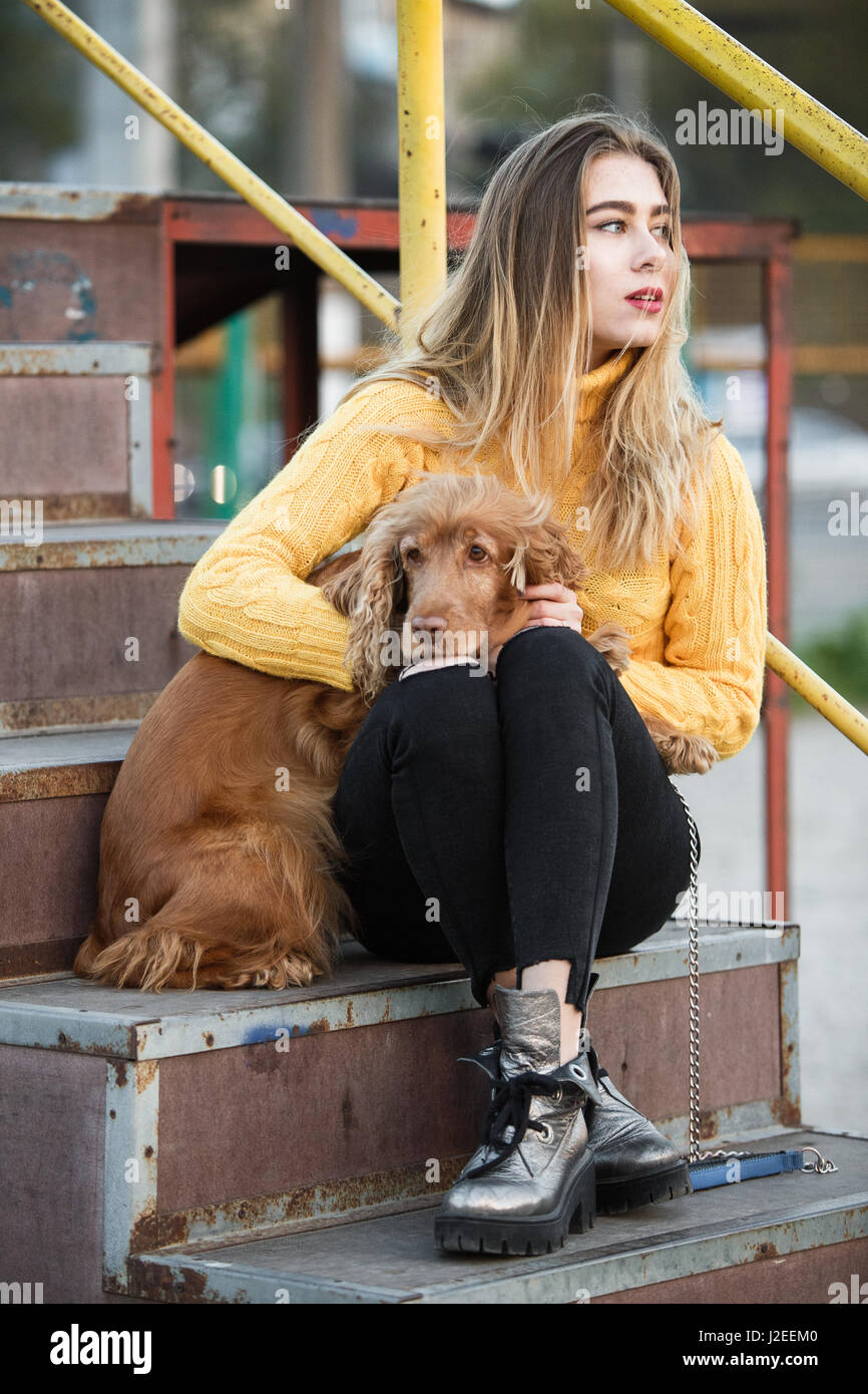Schöne Blondine sah aus wie Jennifer Aniston sitzen mit einem Cocker Spaniel Hund auf eine Metall-Treppe Stockfoto