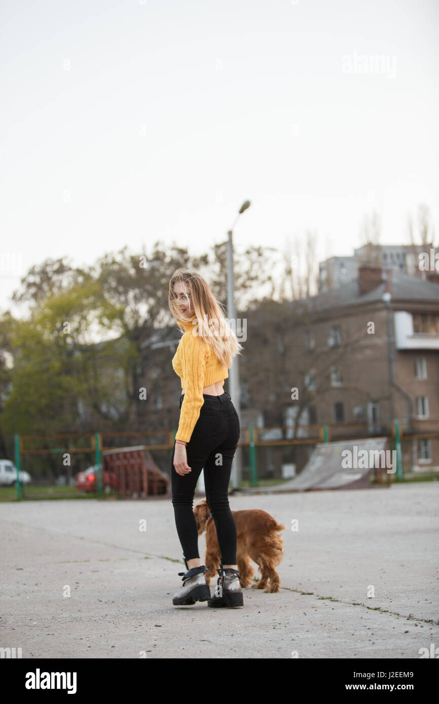 Schöne Blondine sah aus wie Jennifer Aniston steht mit Hund vor Hintergrund der städtischen Häuser Stockfoto
