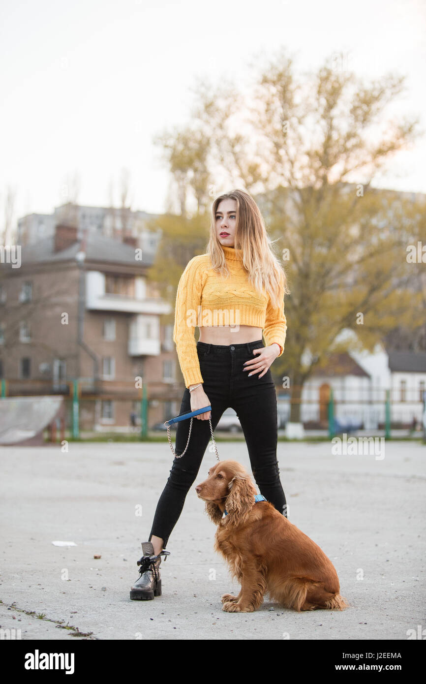 Schöne Blondine sah aus wie Jennifer Aniston steht mit Hund vor Hintergrund der städtischen Häuser Stockfoto