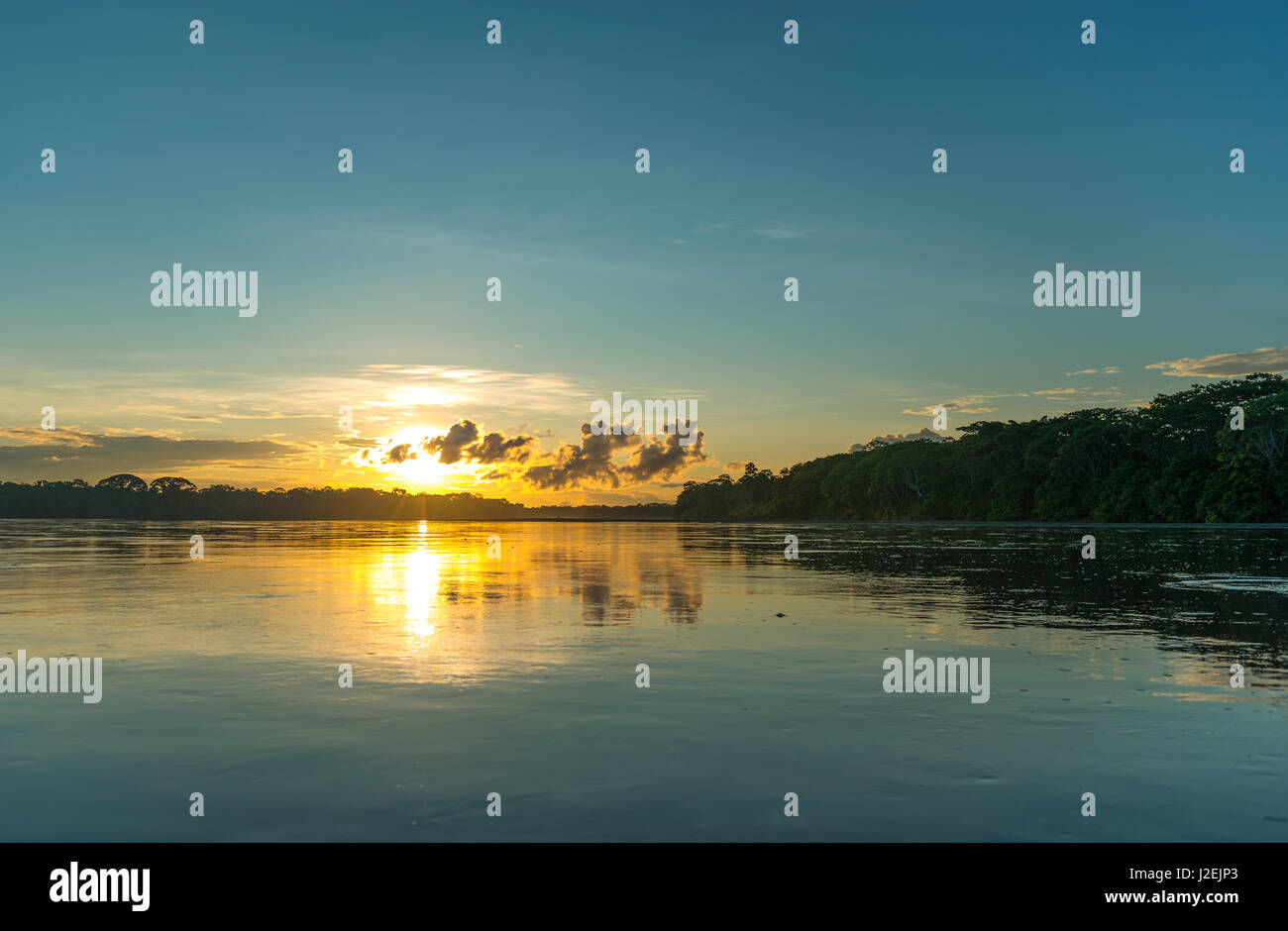 Sonnenuntergang auf dem Amazonas bei einer Bootsfahrt mit einer Betrachtung der Bäume im Wasser. Stockfoto