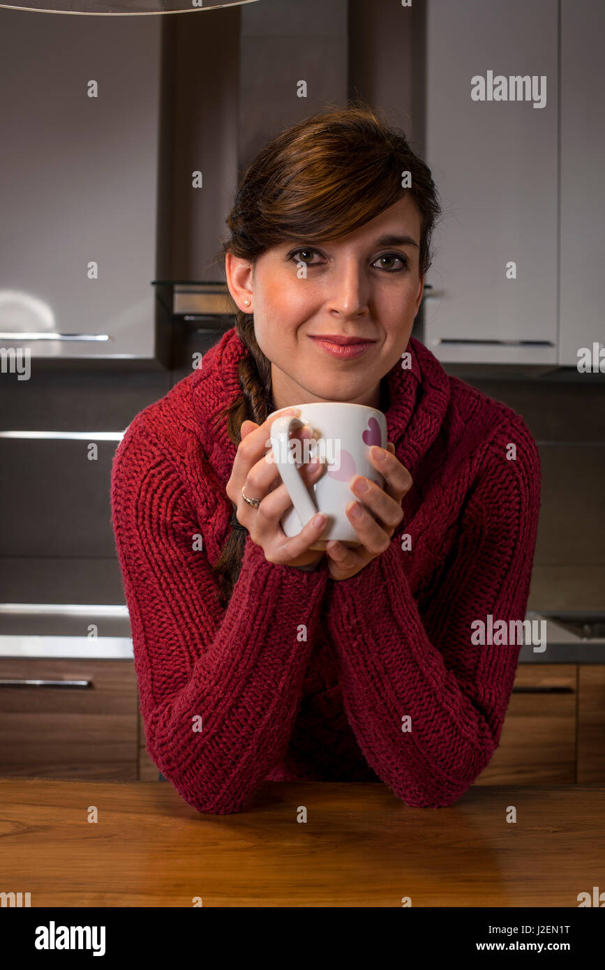 Lächelnde Frau hält mit rosa Herzen Cup in Küche Stockfoto