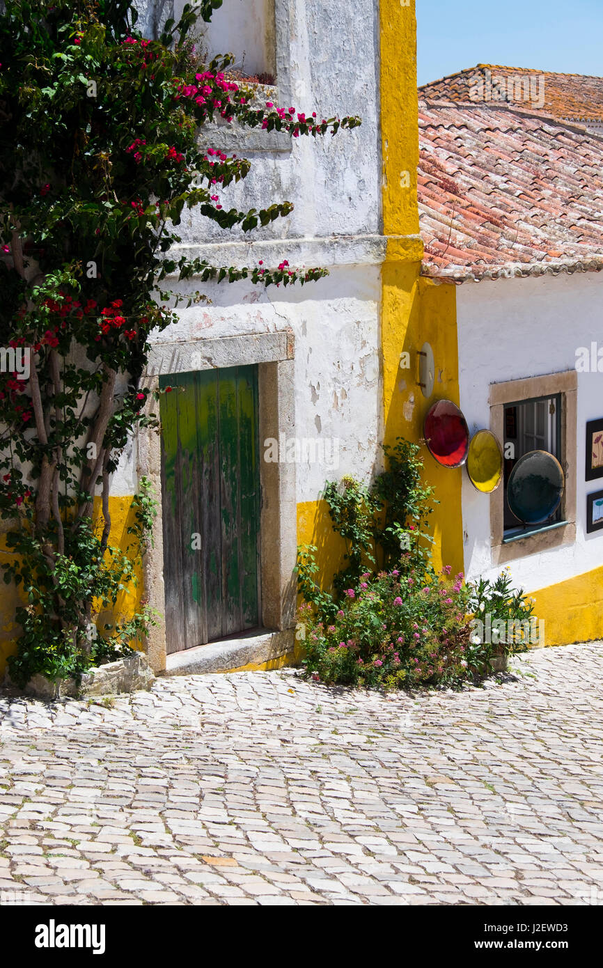 Portugal, Obidos. Leira Bezirk. Kopfsteinpflaster und gewölbte Stege und bunten Blumen in der Nähe von Häusern. Stockfoto