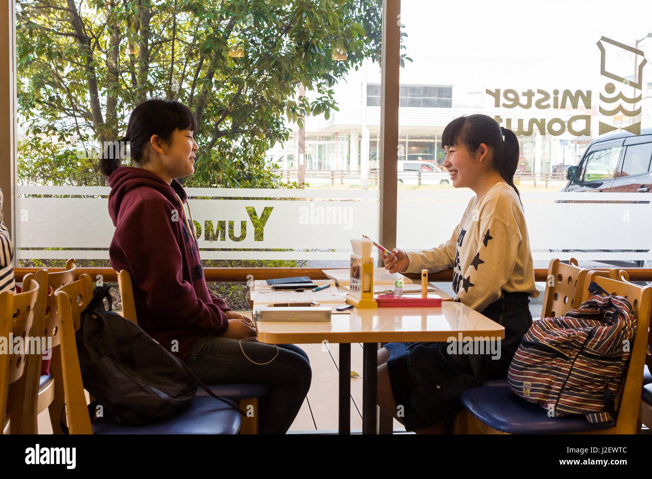 Kanazawa, Japan - 30. März 2017: Japanische Studenten Mädchen sitzen in einem Mister Donut-Coffee-Shop, sprechen und lachen. Stockfoto