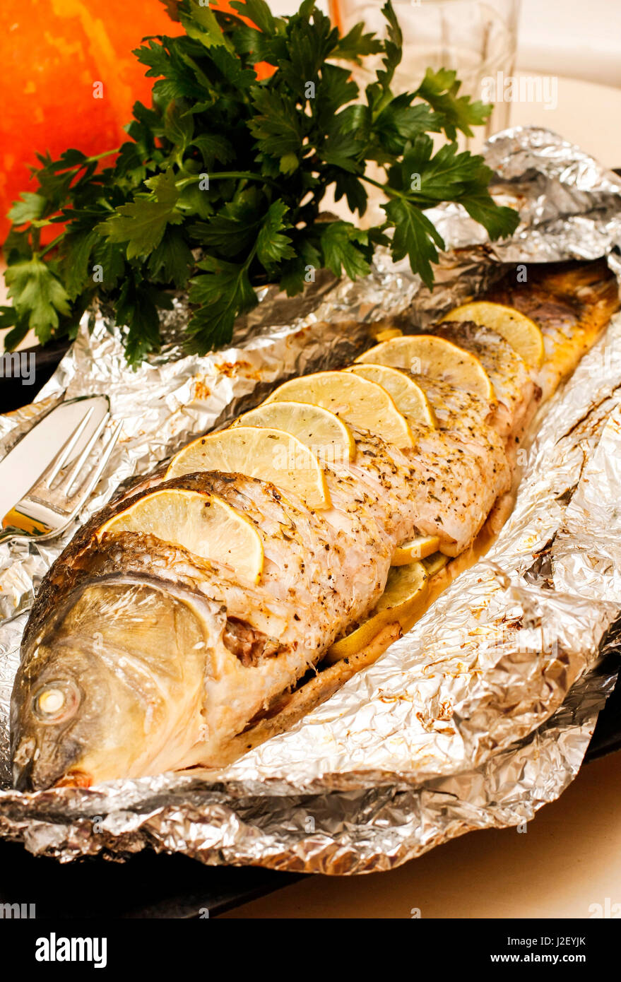 Panierter Karpfen mit Zitrone, Limette und Kräutern auf Folie Stockfoto
