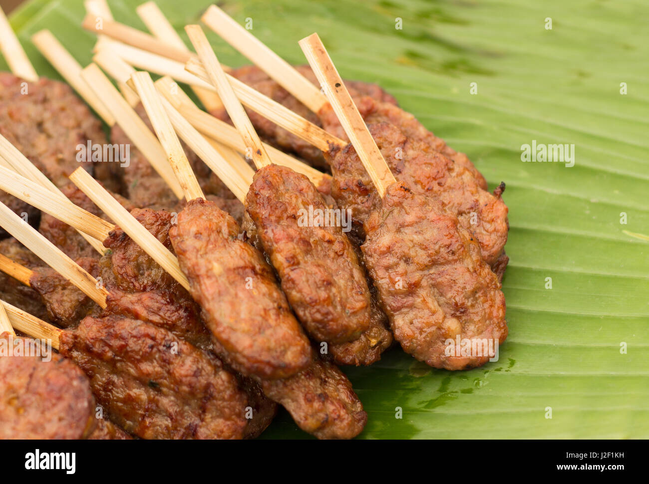 Schließen Sie Schwein Grill mit Holz Stick berühmten schnelle Fingerfood in Thailand auf Bananenblatt Stockfoto