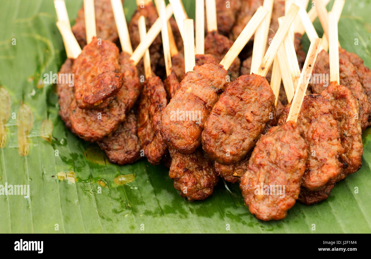 Schließen Sie Schwein Grill mit Holz Stick berühmten schnelle Fingerfood in Thailand auf Bananenblatt Stockfoto