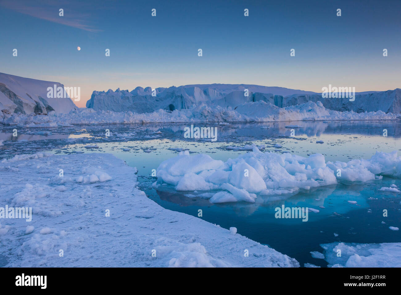 Grönland, Disko-Bucht, Ilulissat, schwimmendes Eis bei Sonnenuntergang mit Mondaufgang Stockfoto