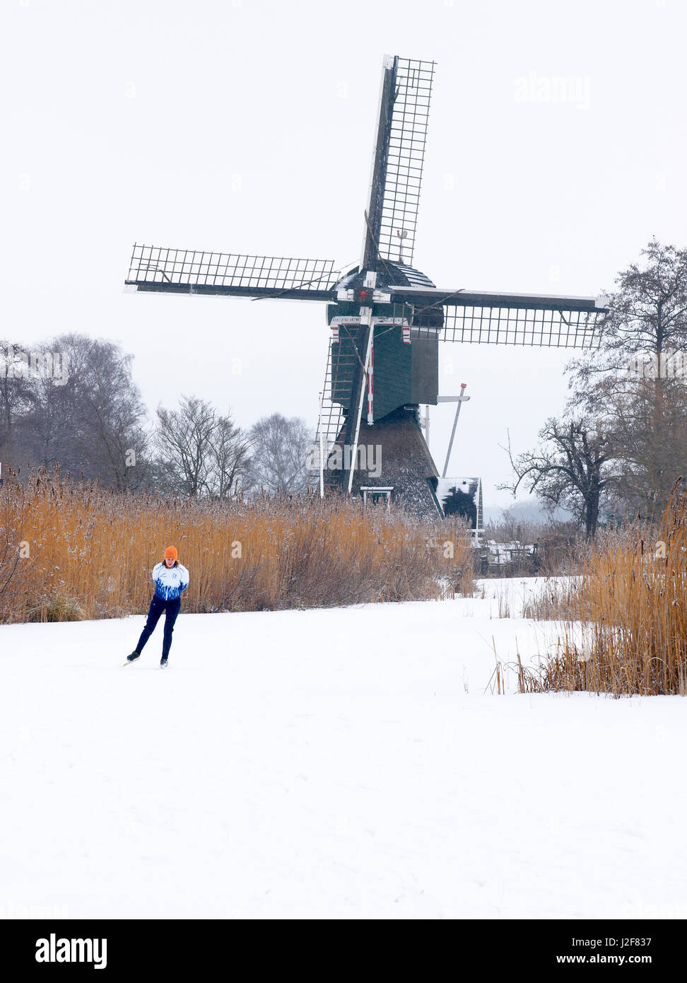 Eis-Skater auf zugefrorenen Kanal und holländischen Windmühle. Stockfoto