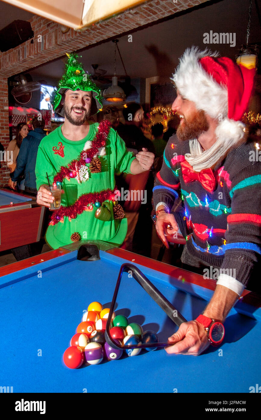 Zwei Pool-Spieler in bunte Weihnachtspullover und Mützen bereiten auf ein Urlaub-Spiel in einem Café in Newport Beach, Kalifornien. Stockfoto