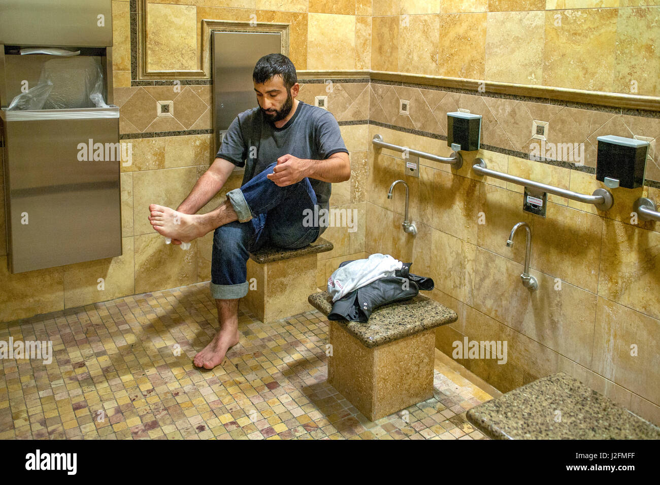 Ein muslimischer Mann bei einem Anaheim, CA, führt Moschee rituelle Waschungen, wie er seine Füße in eine spezialisierte Herrentoilette feierlich als Zeichen der Ehrfurcht vor der Teilnahme an Nachmittag Gebet wäscht. Stockfoto