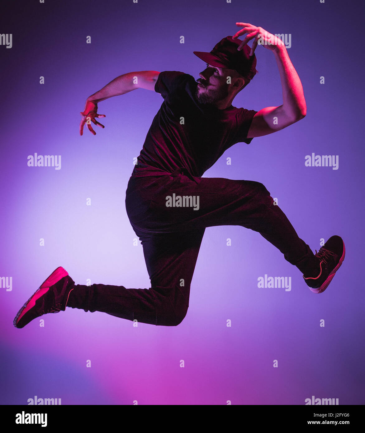 Die Silhouette von einem jungen hip Hop männlichen Pause Tänzer tanzen auf farbigen Hintergrund Stockfoto