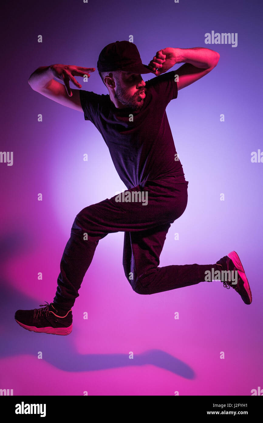 Die Silhouette von einem jungen hip Hop männlichen Pause Tänzer tanzen auf farbigen Hintergrund Stockfoto