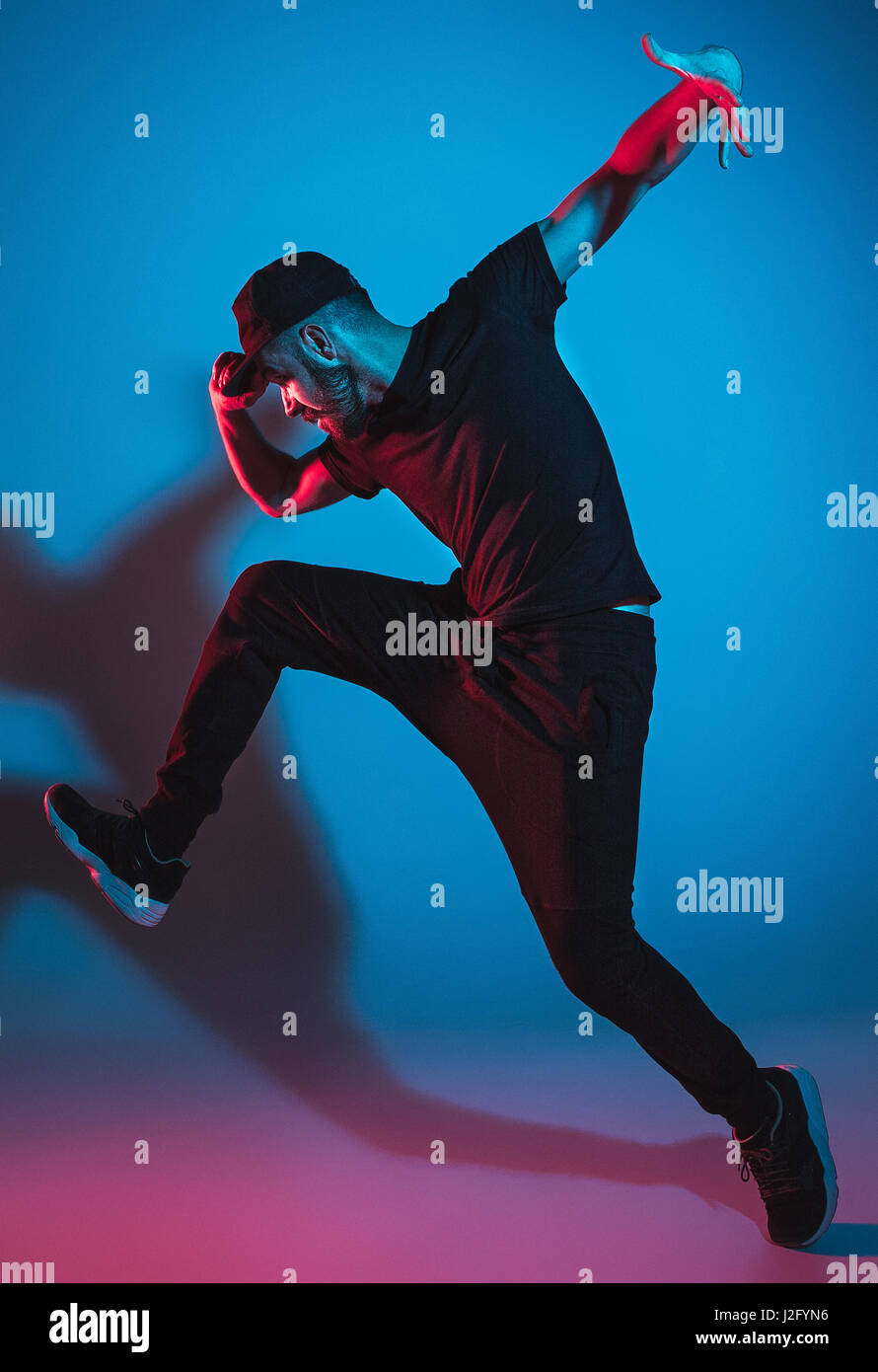 Die Silhouette von einem jungen hip Hop männlichen Pause Tänzer tanzen auf farbigen Hintergrund Stockfoto