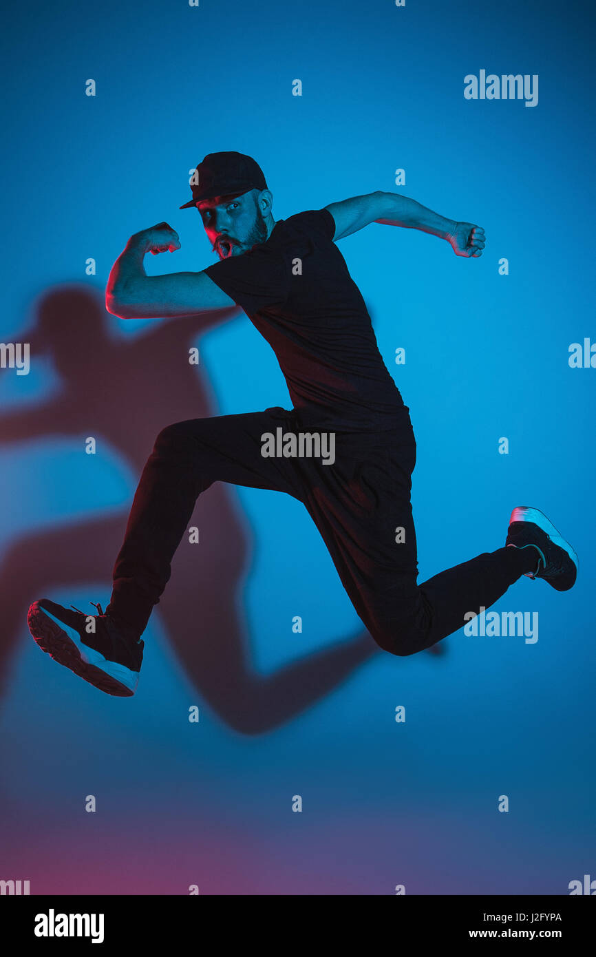 Die Silhouette von einem jungen hip Hop männlichen Pause Tänzer tanzen auf farbigen Hintergrund Stockfoto