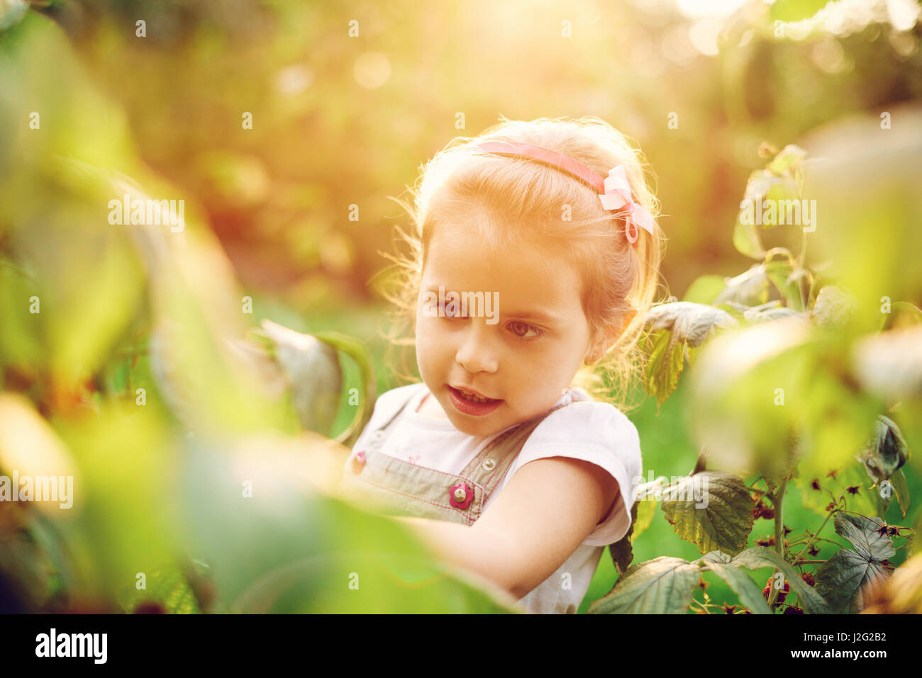 Reportageaufnahme eines schönen Mädchens Blick auf Pflanzen in einem Garten Stockfoto