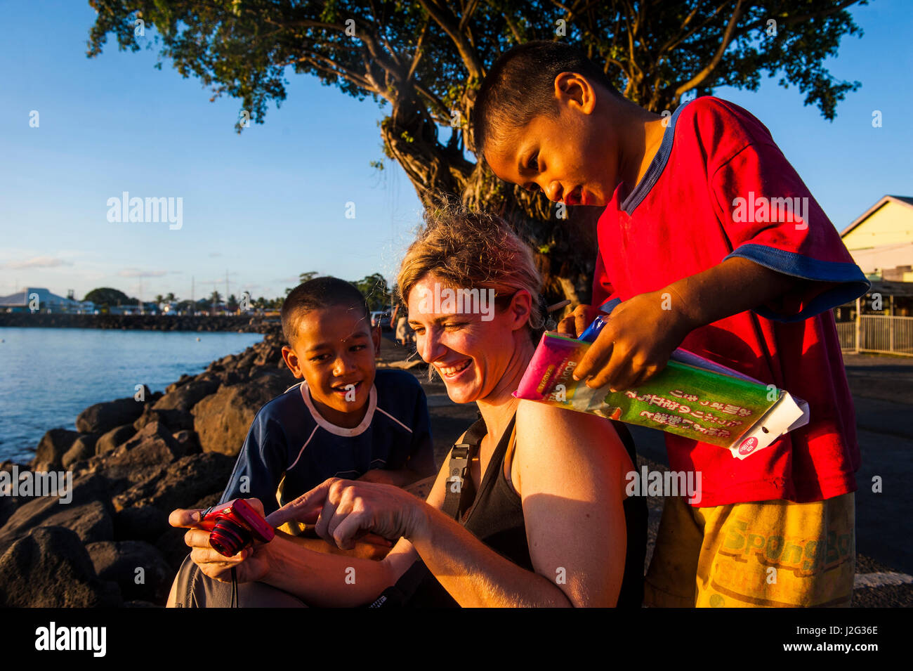 Westliche Frau zeigt Fotos auf eine Digi-Cam zu lokalen Jungs, Upolu, Samoa, Apia, Süd-Pazifik. (MR) Stockfoto