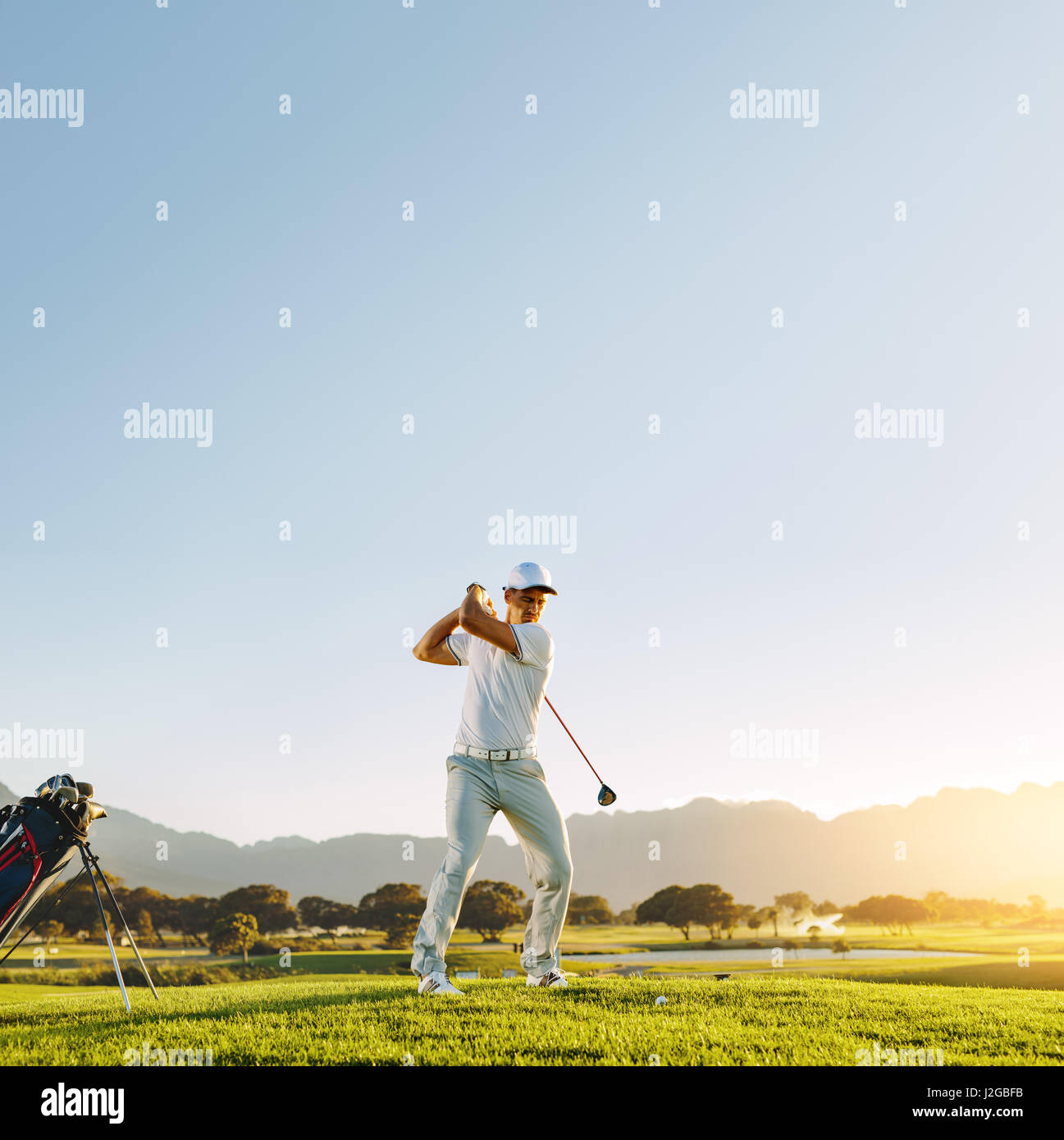Porträt des männlichen Golfspieler Abschlag-off mit Fahrer. Profi-Golfer unter Schuss stehend auf Feld. Stockfoto