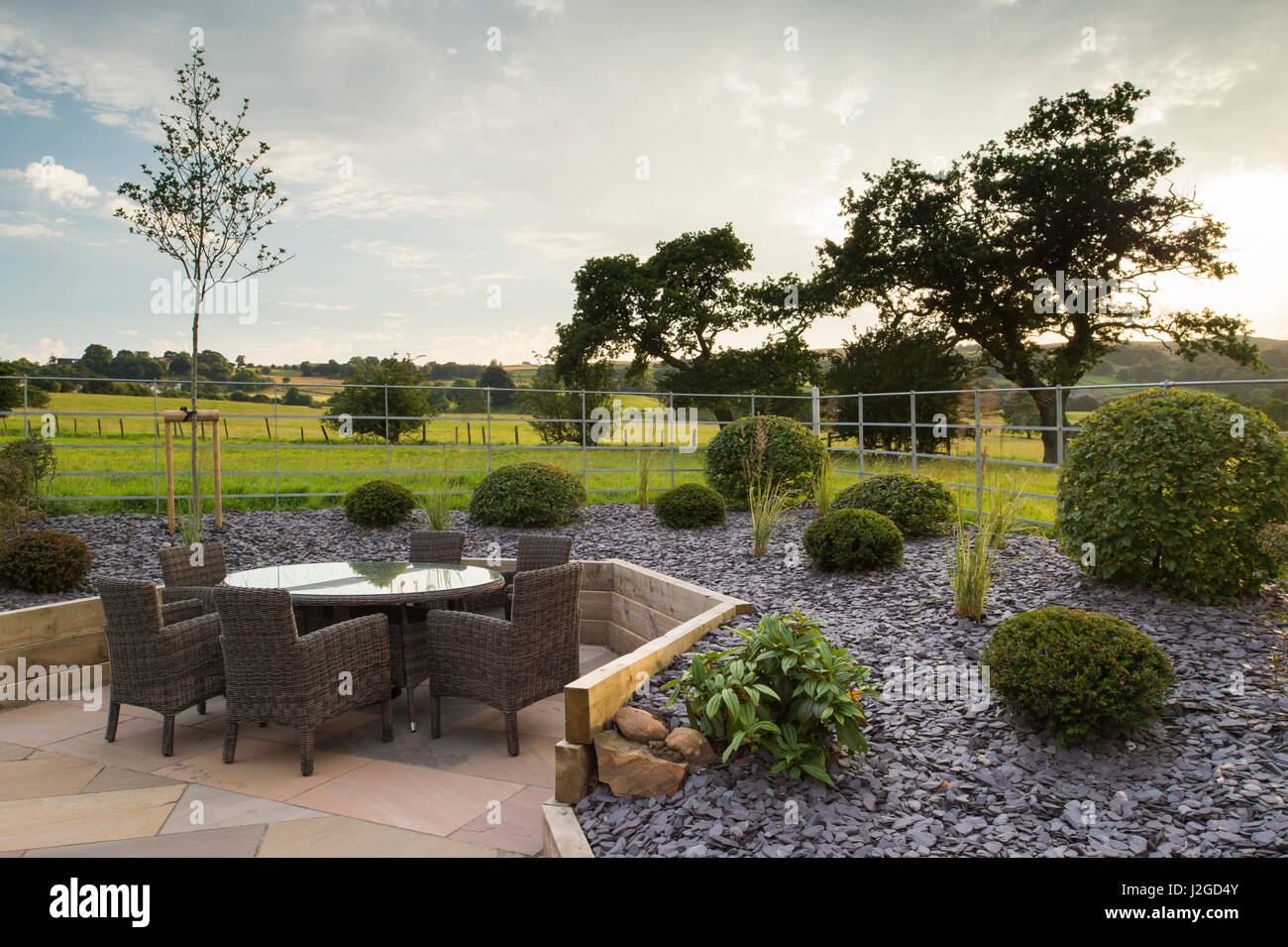 Schöne, Private, zeitgenössische gestalteten, Garten, England, GB, UK - Lieferservice (Patio-Möbel) angehoben, Grenzen, Gräser & topiary Sträuche. Stockfoto