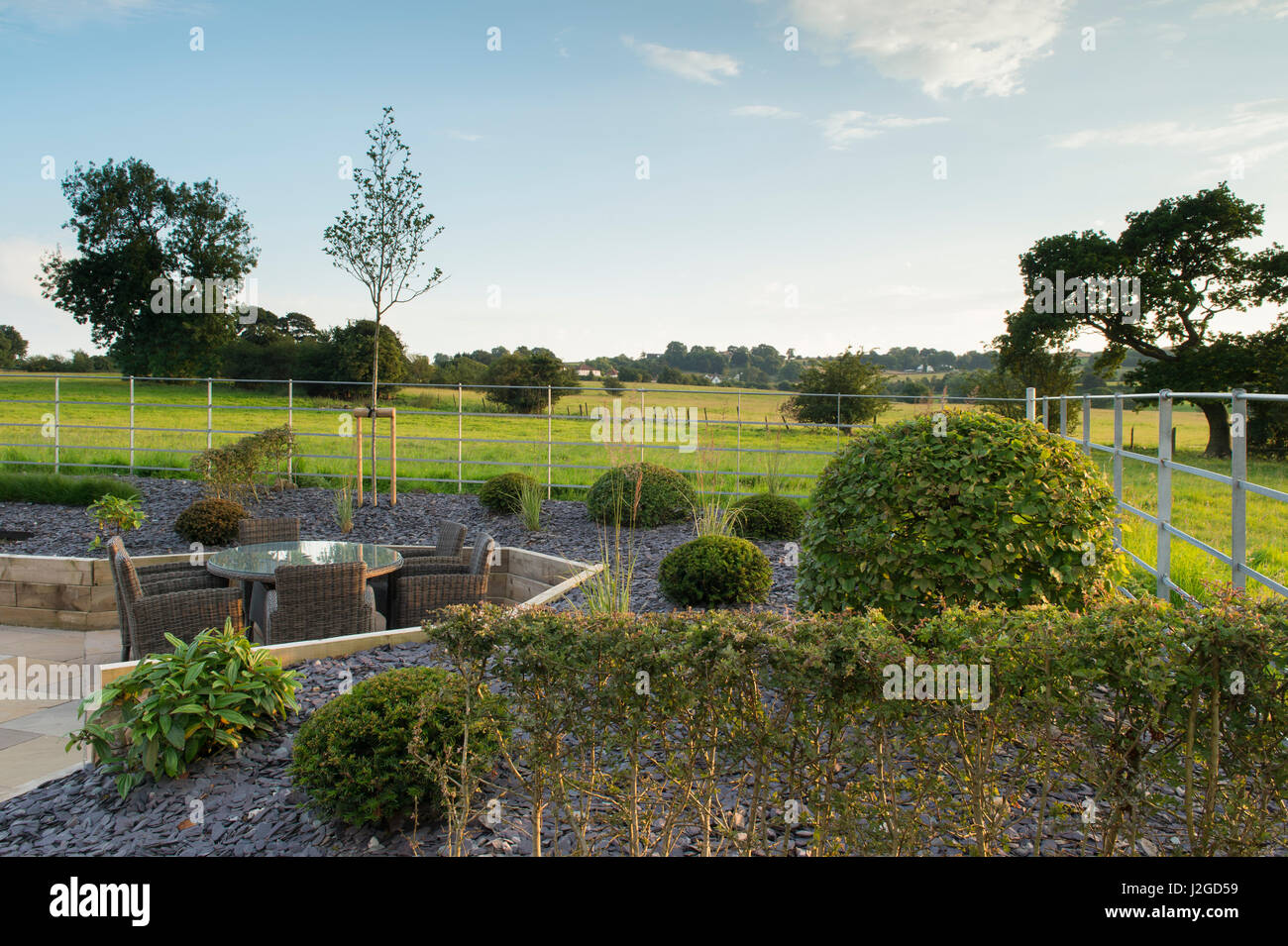 Schöne, Private, zeitgenössische gestalteten, Garten, England, GB, UK - Lieferservice (Patio-Möbel) angehoben, Grenzen, Gräser & topiary Sträuche. Stockfoto