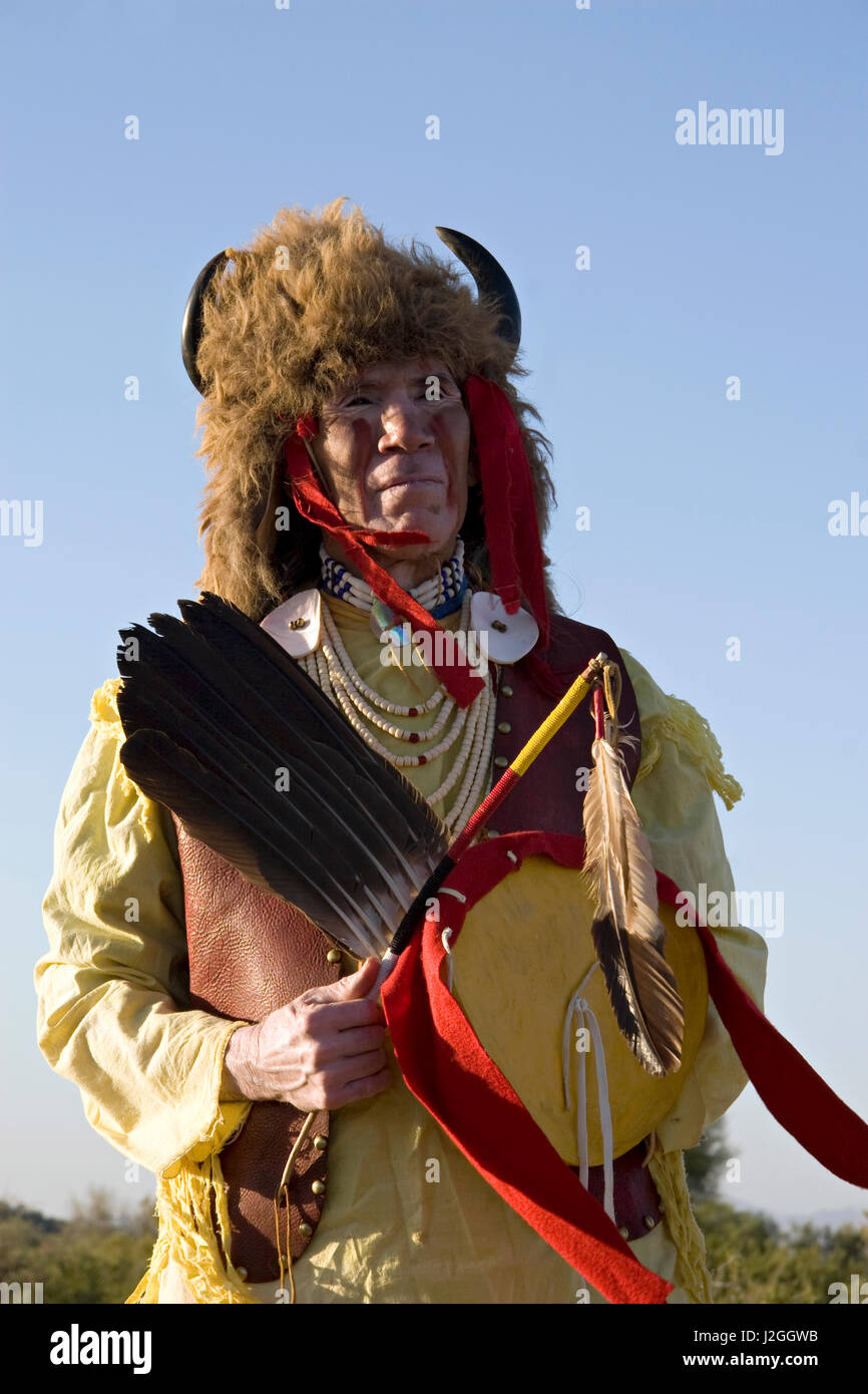 Porträt eines amerikanischen Indianer Mann der Sioux Nation in traditionellen Krieg Hemd, Ponyperlen und Büffel Kopfschmuck gekleidet hält einen Medizin-Stick und Rohhaut Schild (MR) Stockfoto