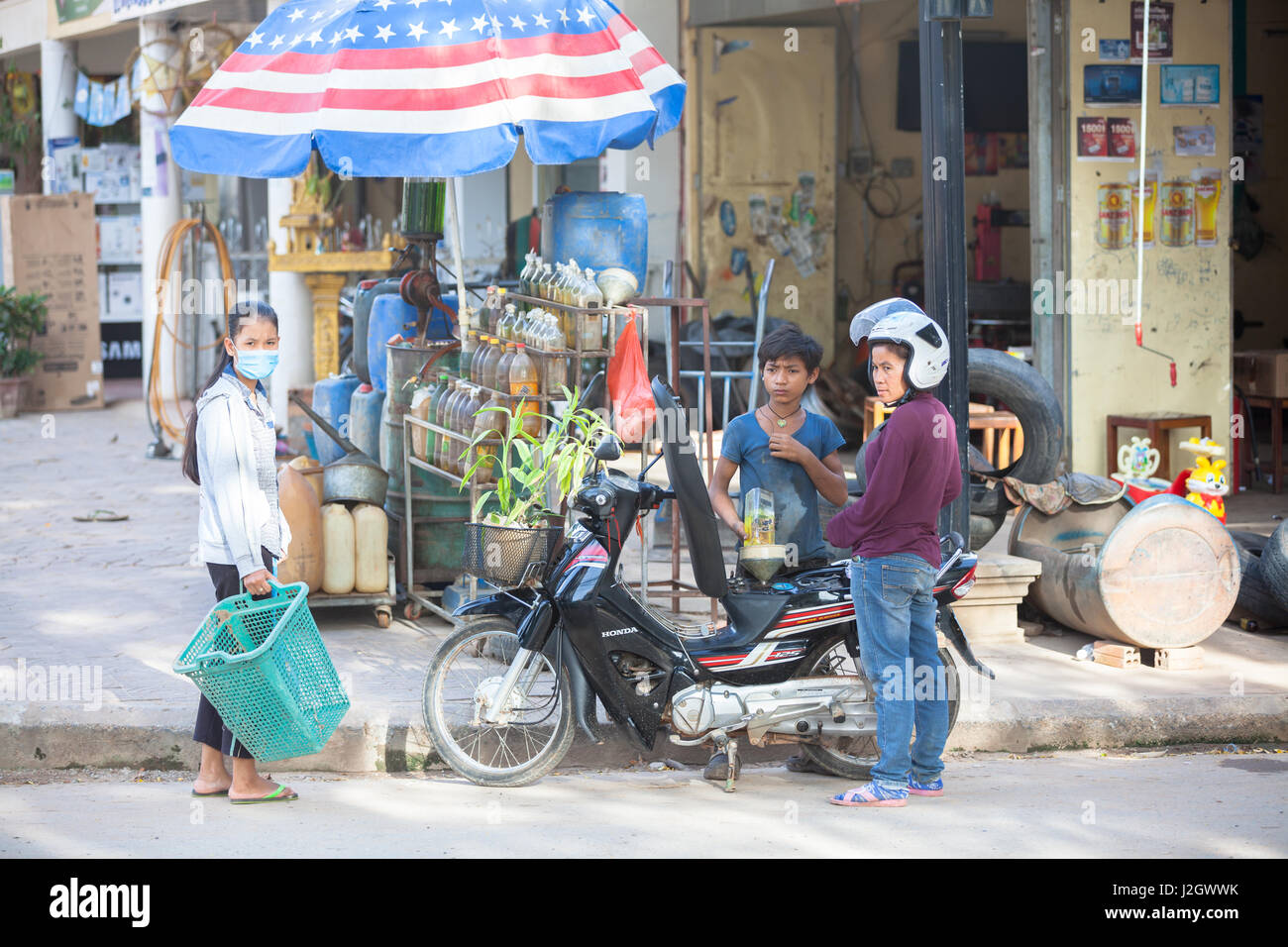SIEM REAP, Kambodscha - Juli 6: Junge Frau Motorrad aus der Flasche auf traditionellen asiatischen Tankstelle tanken, am 6. Juli 2014 in Siam Reap, Kambodscha. Stockfoto
