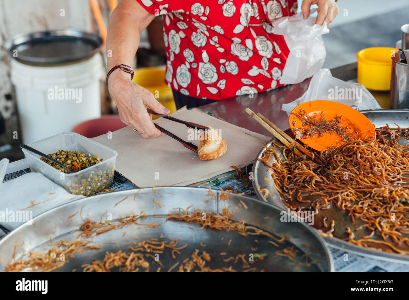 GEORGE TOWN, MALAYSIA - 23 März: Frau Verpackung Curry Blätterteig bis die Plastiktüte auf Kimberly Street Food Nachtmarkt am 23. März 2016 in George Town, M Stockfoto