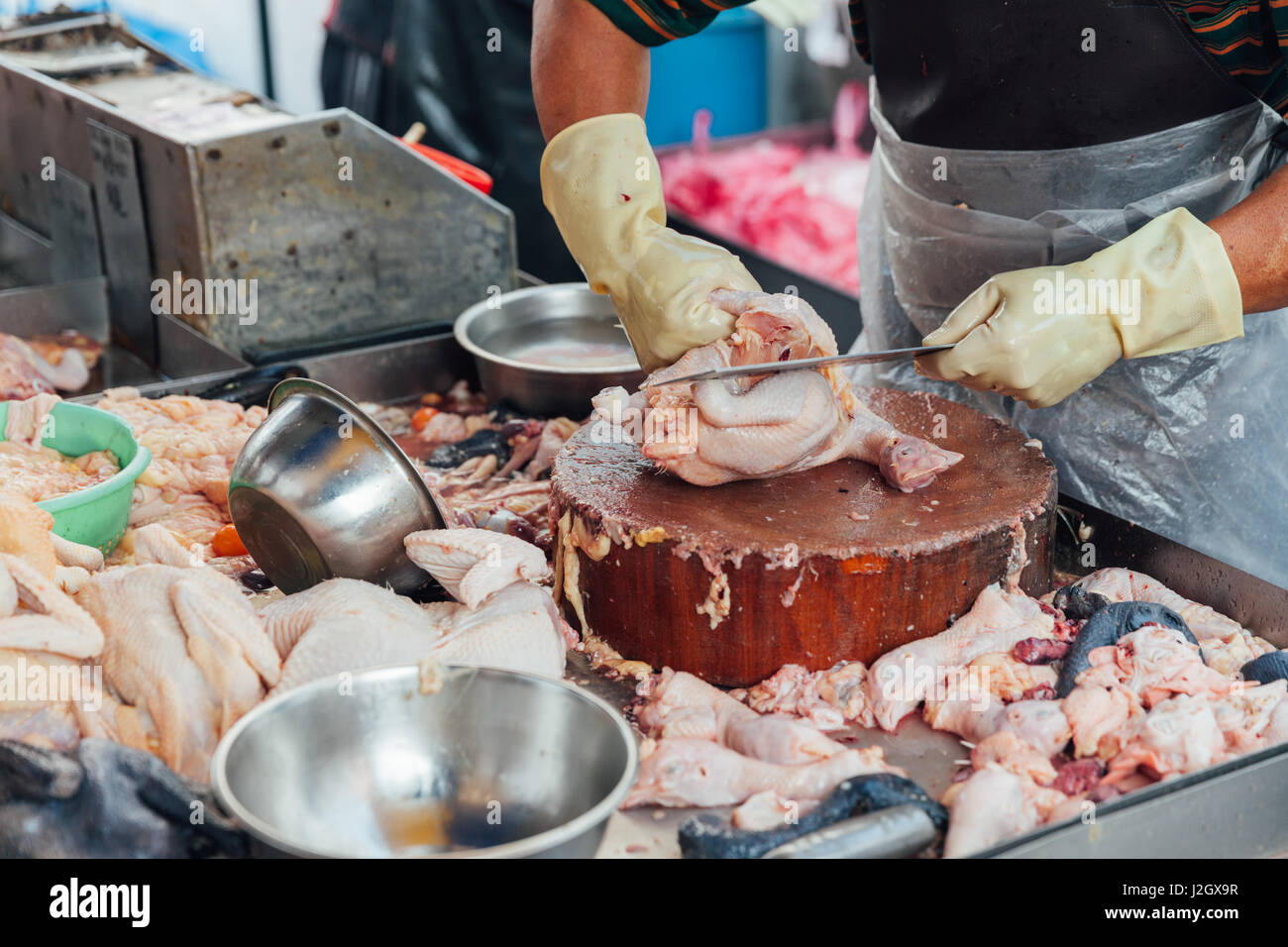 Metzger trennt Stücke von rohem Hühnerfleisch zum Verkauf auf dem nassen Markt von George Town, Penang, Malaysia. Stockfoto