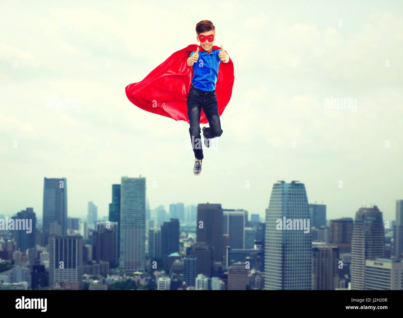 Junge in Superhelden Cape und Maske, die Daumen nach oben zeigen Stockfoto
