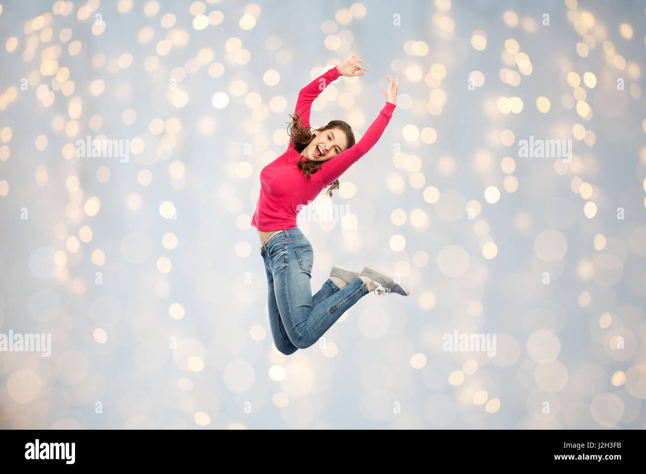 glückliche junge Frau springen oder tanzen über Lichter Stockfoto
