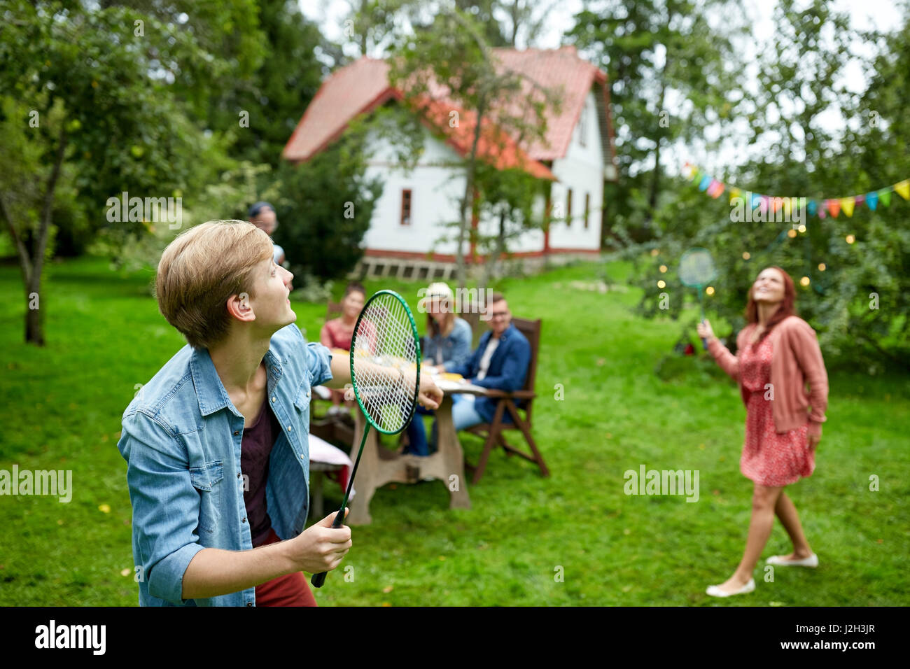 Glückliche Freunde spielen Badminton im Sommergarten Stockfoto