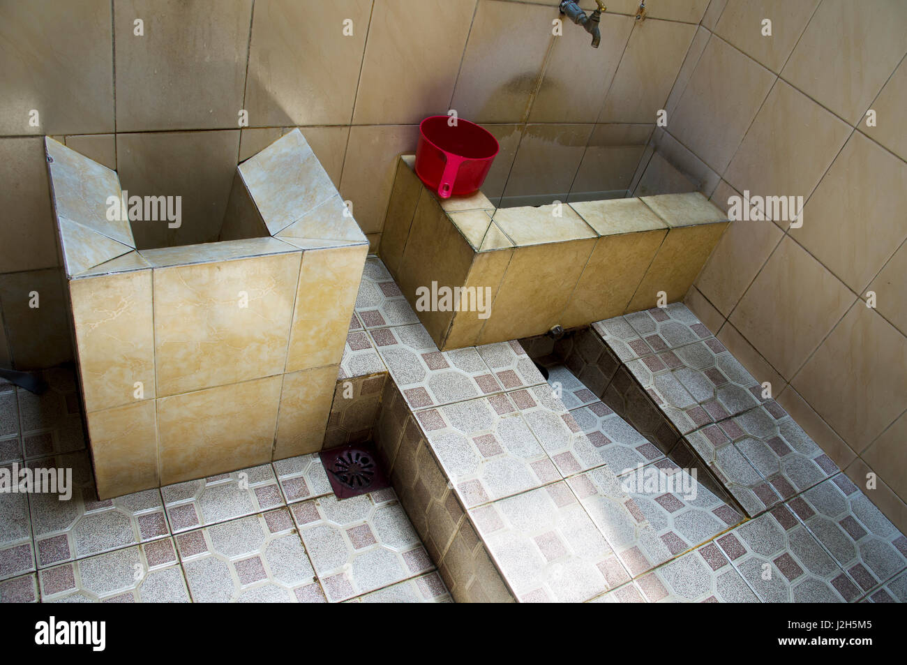 Asiatische geflieste Badezimmer und roten Eimer mit Wasser füllen und waschen Sie sich mit. Stockfoto