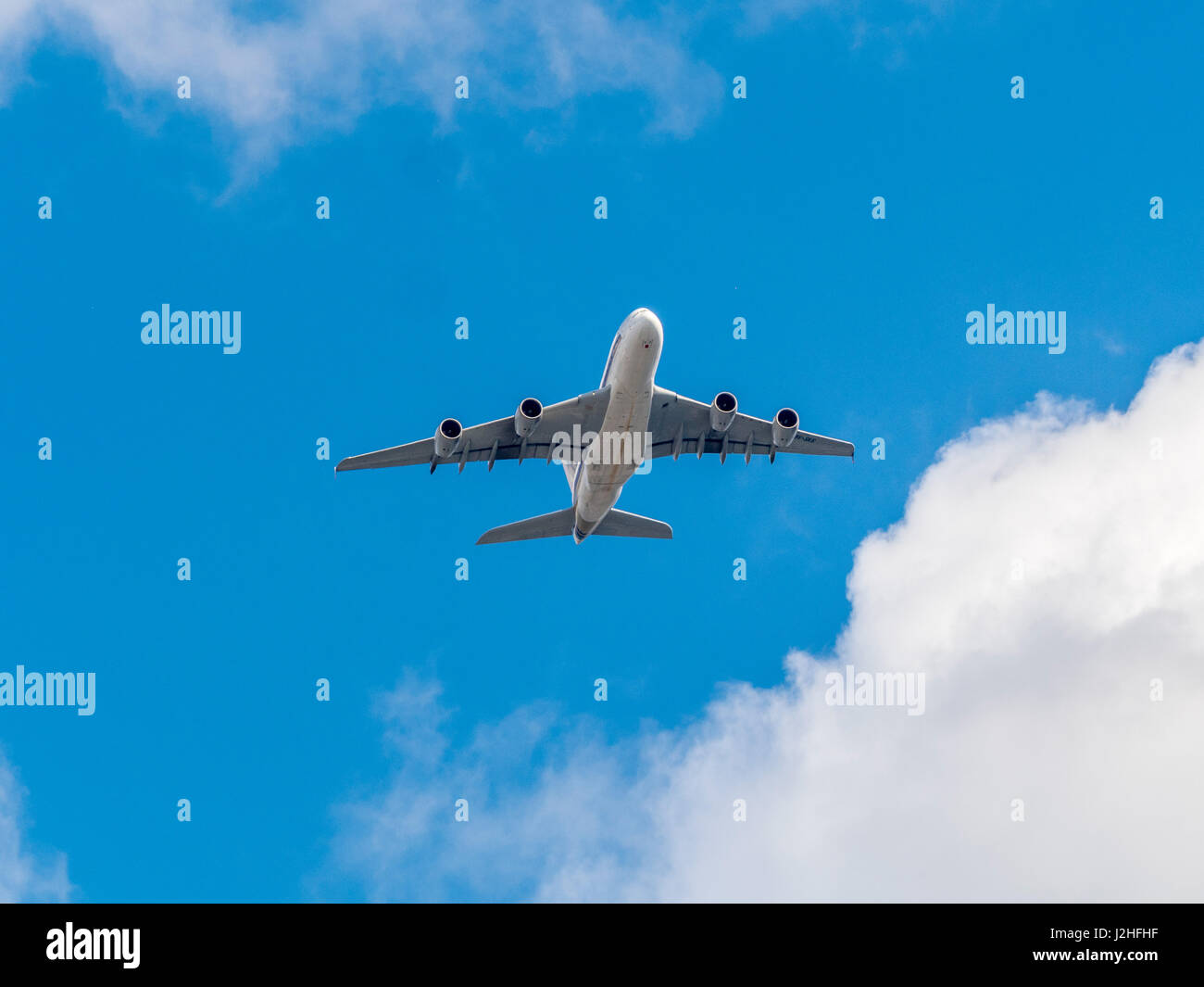 Jet-Passagierflugzeug gegen blauen Himmel mit Wolken von unten gesehen. Stockfoto