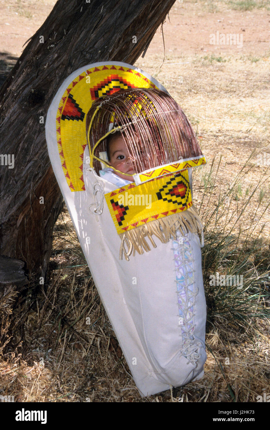 Native American Baby innerhalb einer traditionellen Weide Kindertrage geschnürt mit bunten gelben Perlenstickerei verziert Stockfoto