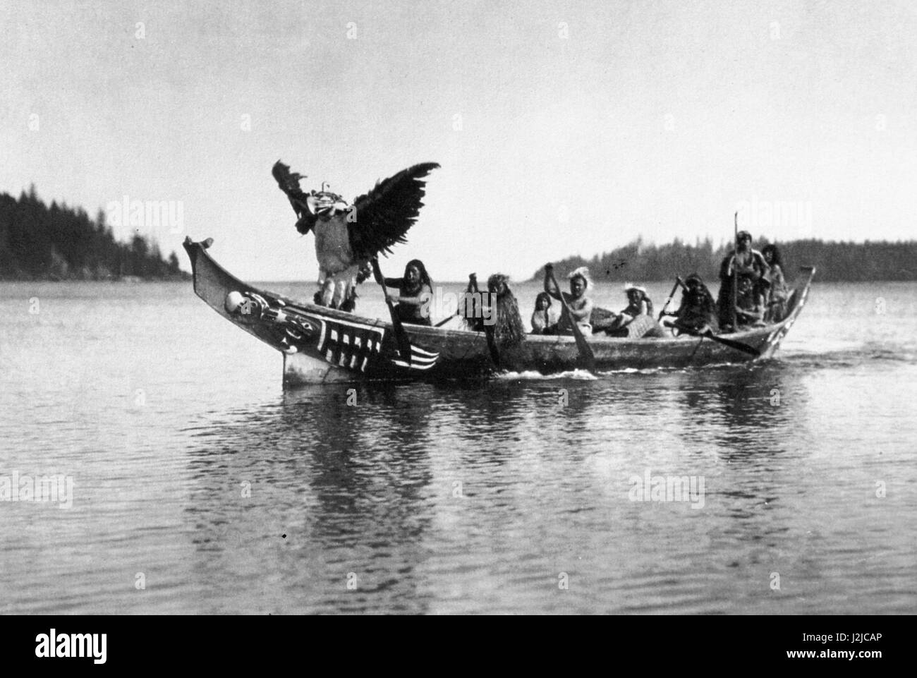 Historisches Foto von Curtis des Pazifischen Nordwestens Kanu mit einem Adler-Tänzer und traditionell gekleidete Männer paddeln. Vancouver Island, BC, Kanada Stockfoto