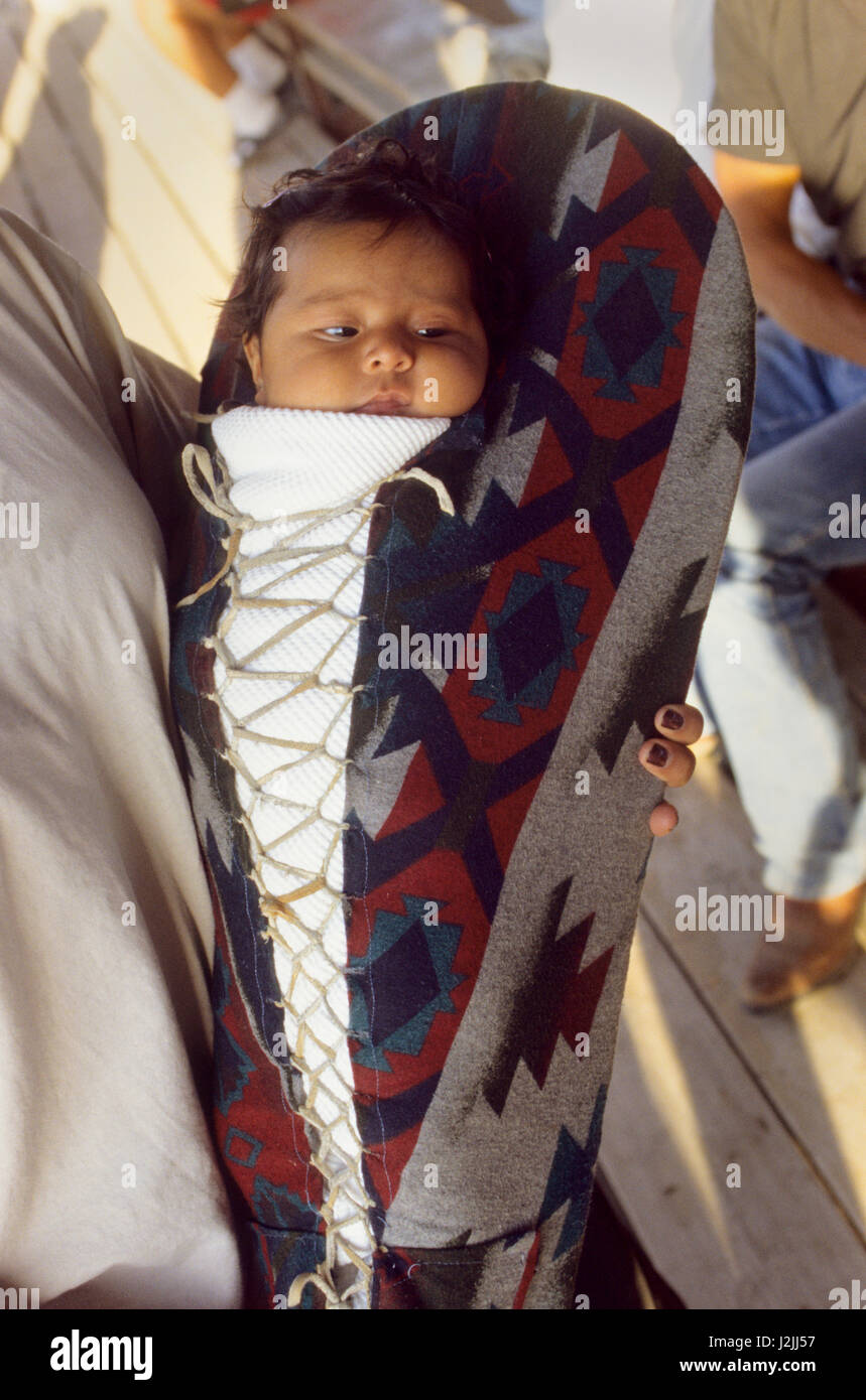 Native American Baby innerhalb einer traditionellen Kindertrage mit einer Pendleton Decke bedeckt geschnürt wird in die Arme Mütter gehalten. (MR) Stockfoto