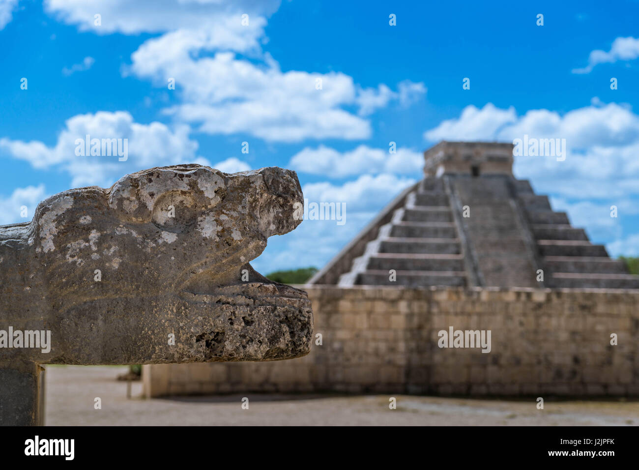 Jaguar-Kopf ragt aus einer Umfassungsmauer Gran Juego de Pelota ("großer Ballspielplatz"), mit El Castillo in Chichén Itzá (Mexiko) im Hintergrund Stockfoto