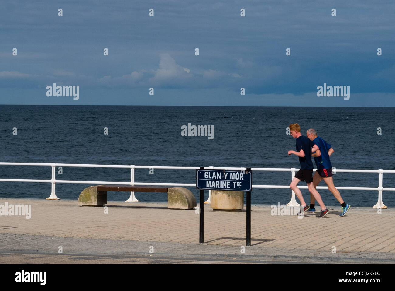 Aberystwyth Wales UK, Samstag, 29. April 2017 UK Wetter - zwei Personen genießen Sie Joggen an einem hellen sonnigen, aber windigen Morgen am Meer in Aberystwyth zu Beginn der Mayday Bank Holiday Wochenende Photo Credit: Keith Morris/Alamy Live-Nachrichten Stockfoto