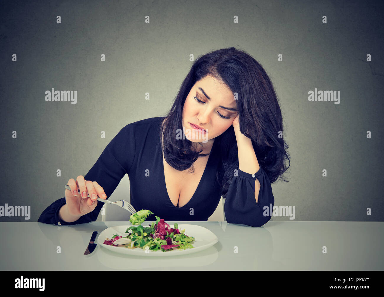 Junge Frau Essen grünen Blattsalat müde Diätbeschränkungen unzufrieden Stockfoto