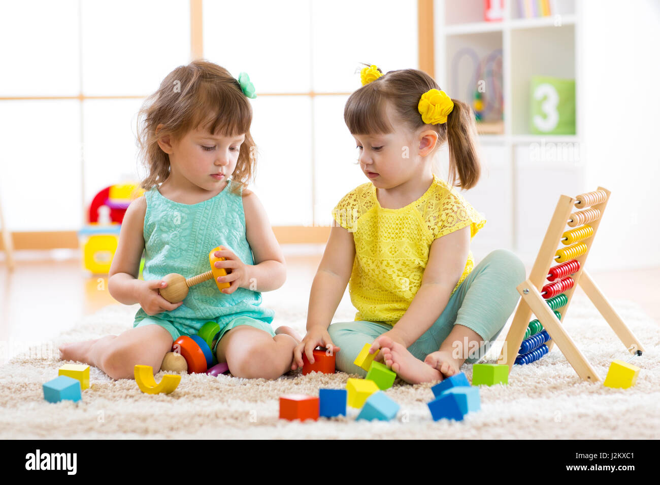 Kinder spielen mit Bausteinen. Pädagogische Spielwaren für Kinder von Vorschule und Kindergarten. Kleine Mädchen bauen Spielzeug daheim oder Kindertagesstätten. Stockfoto