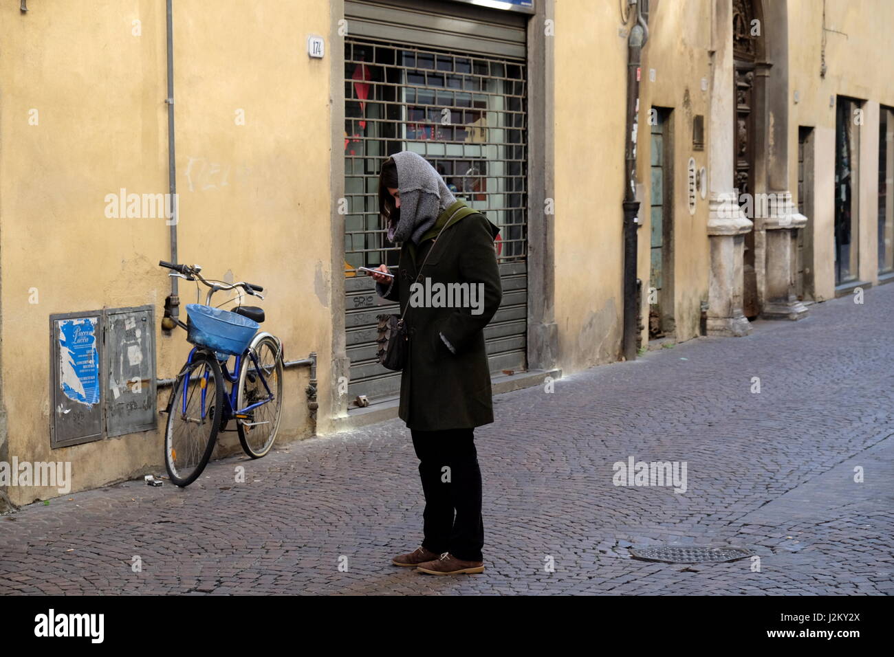 Mädchen (junge Frau) SMS auf Smartphone auf der Straße - spontane ungestellte Fotografie, zentrale Lucca, Toskana, Italien, Europa Stockfoto