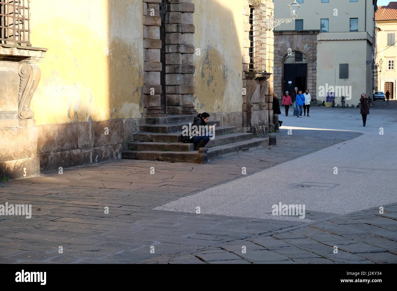 Mädchen (junge Frau) SMS auf Smartphone auf der Straße - spontane ungestellte Fotografie, zentrale Lucca, Toskana, Italien, Europa Stockfoto