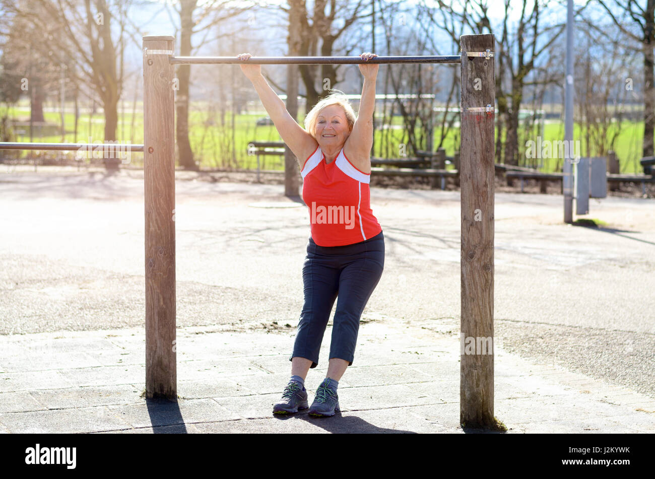 Beautiful senior Woman arbeiten auf einer horizontalen Leiste in einer ländlichen Sportarena in ein Fitness und gesunde Lebensweise-Konzept Stockfoto