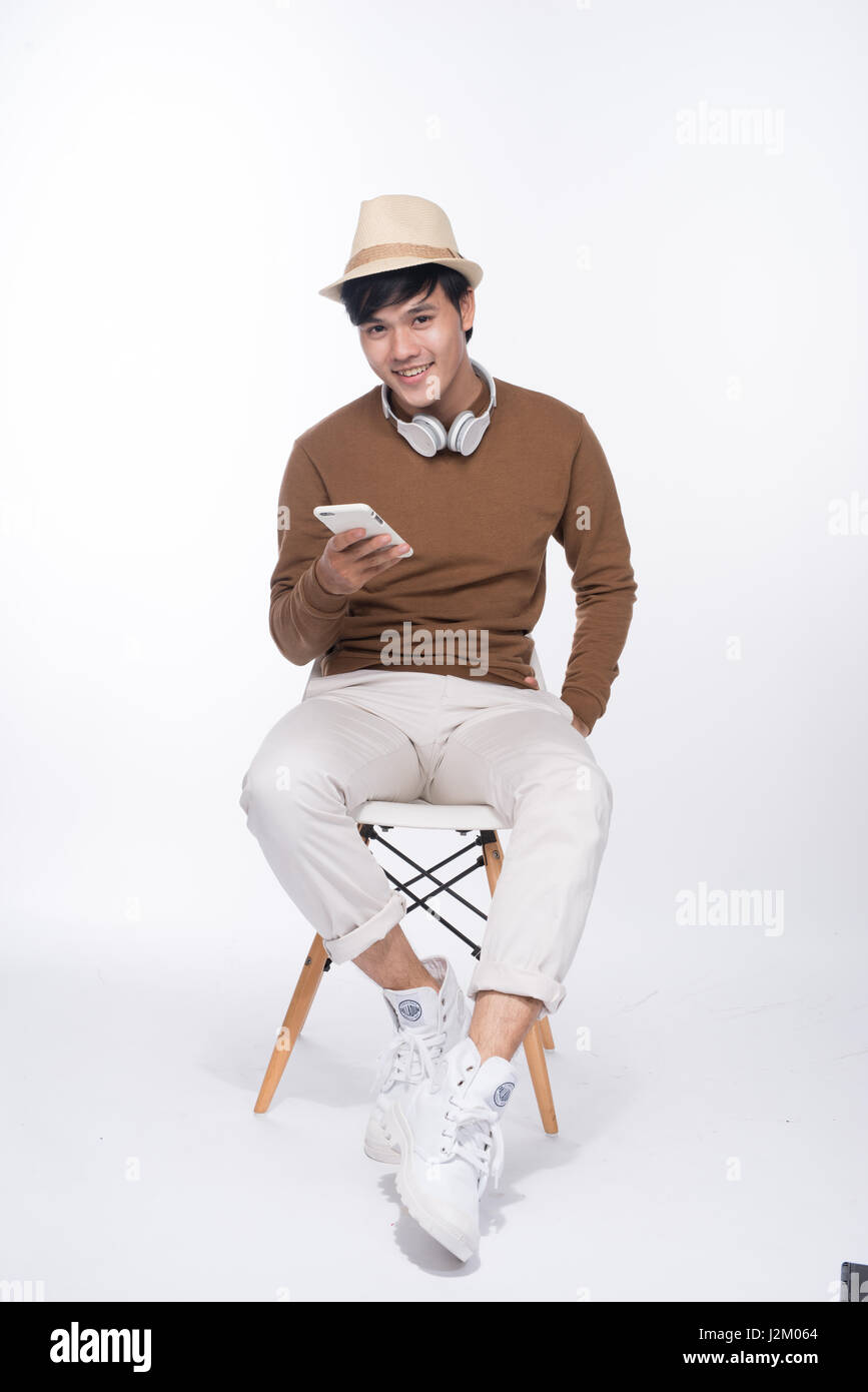 Smart Casual asiatischer Mann auf Stuhl sitzen, im Studio Hintergrund smartphone Holding Stockfoto