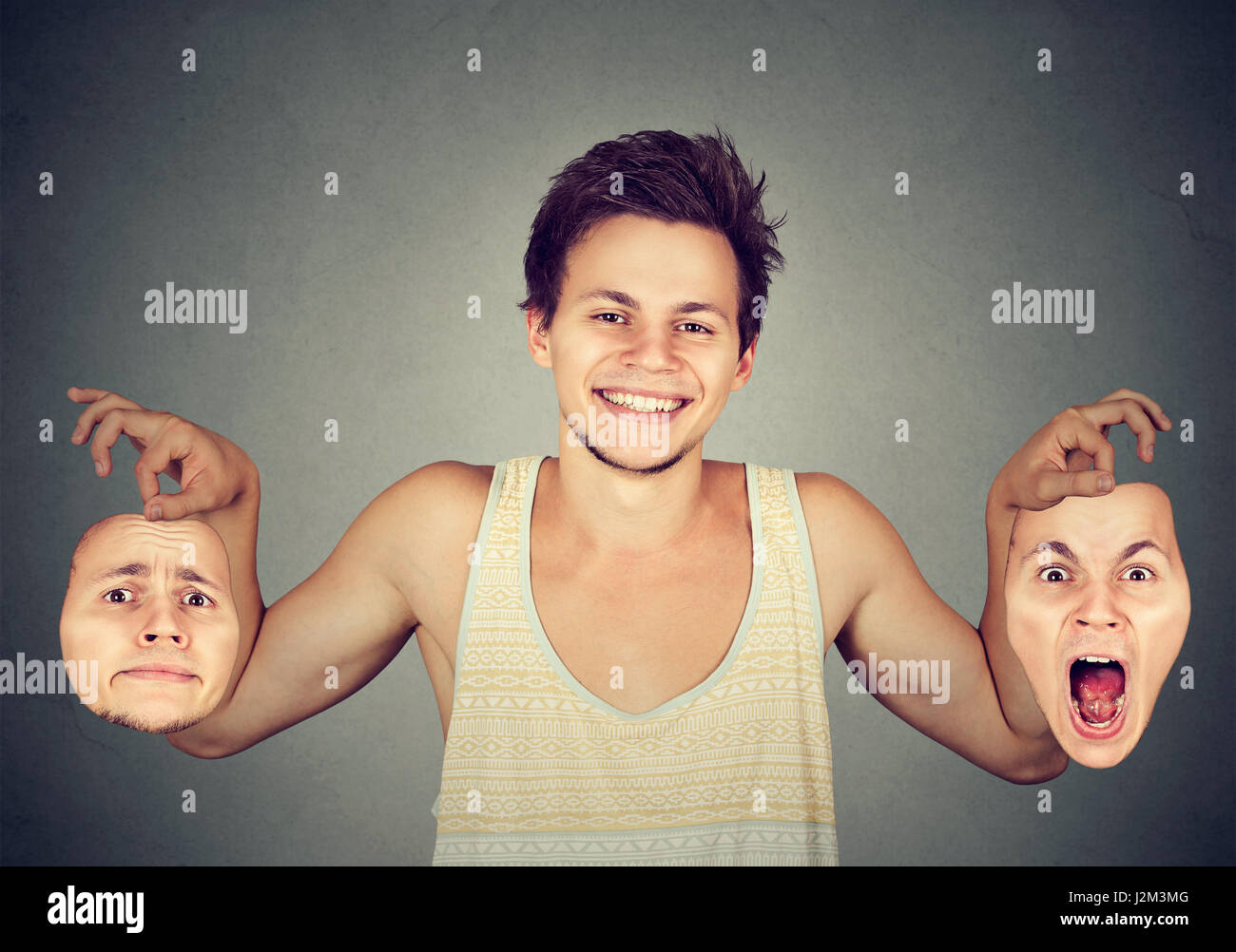 Lächelnder Mann hält zwei verschiedene Emotionen Masken Stockfoto