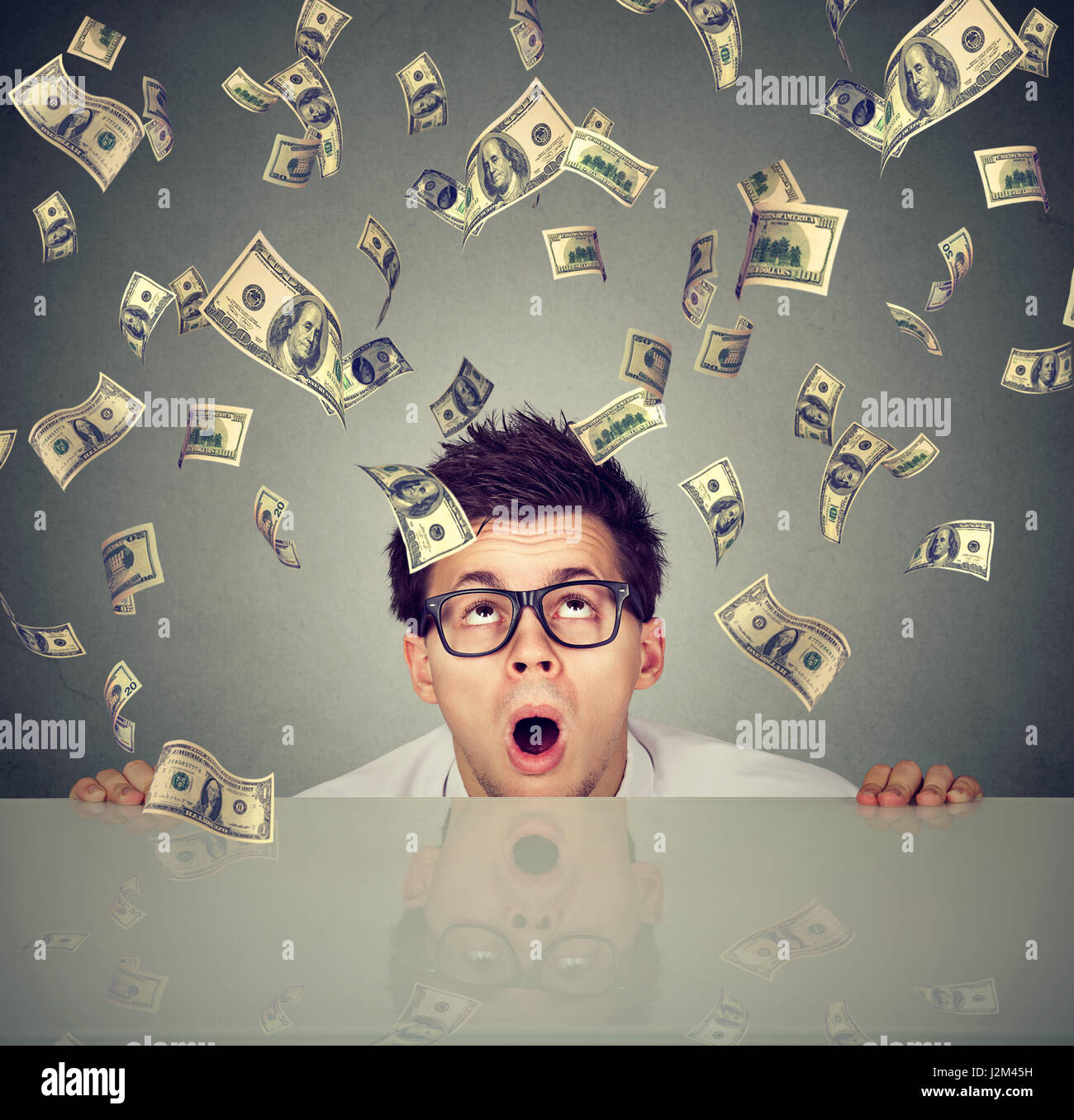 Überrascht Man unter Geld Regen spähen unter dem Tisch Stockfoto