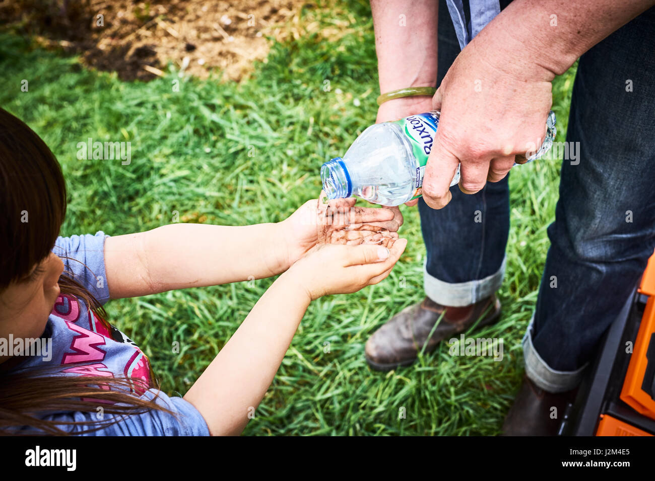 Junges Mädchen waschen schlammige Fingern am britischen Zuteilung mit Wasserflasche. Stockfoto